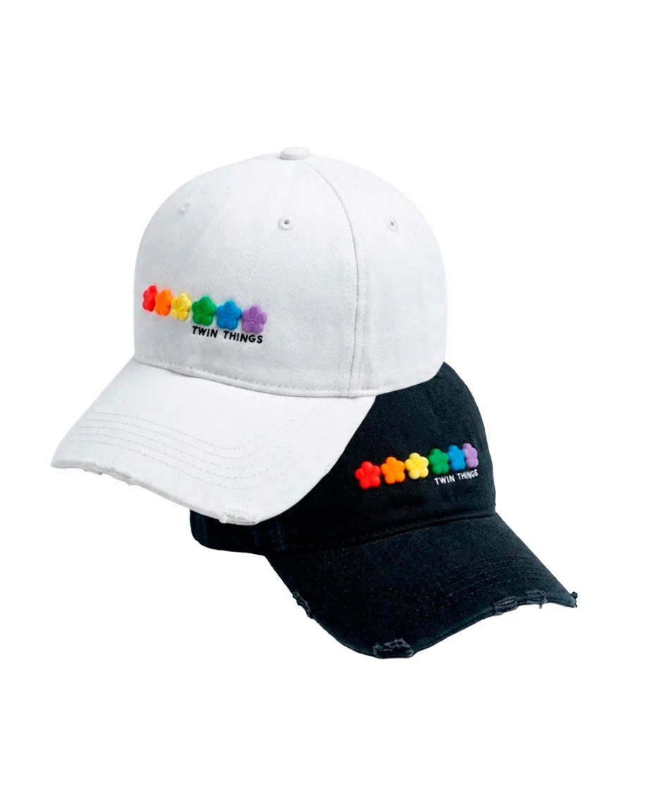 Coppia di dad cap Twin Things, uno bianco e uno nero, con fiorellini in 3D arcobaleno e logo TWIN THINGS piccolo sotto